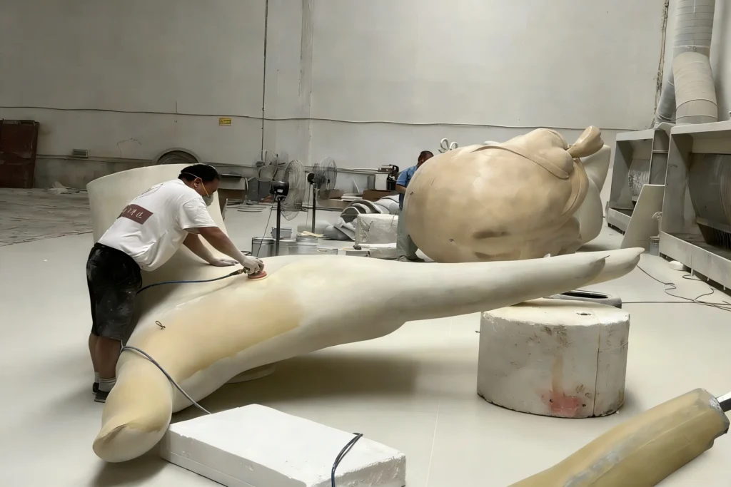 Professional fiberglass sculpture manufacturer, skilled technician sanding fiberglass sculpture surface for perfect finish